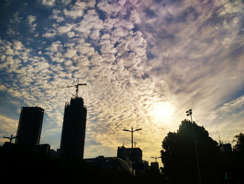 Low angle view of crane against cloudy sky