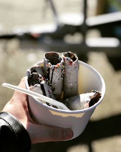 Cropped hand holding ice cream in bowl outdoors