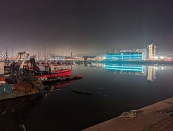 Sailboats moored in harbor at night