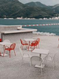 Empty chairs and table by swimming pool