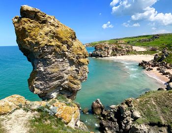 Rock formation on beach against sky