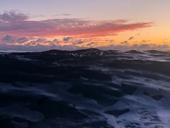 Scenic view of sea against dramatic sky during sunset