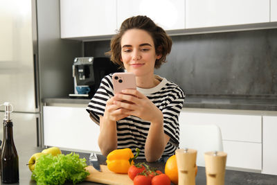 Portrait of young woman using mobile phone at home