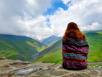 Rear view of woman looking at mountains against sky