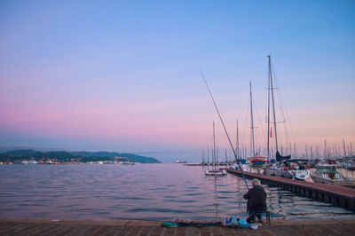 Boats in calm sea at sunset