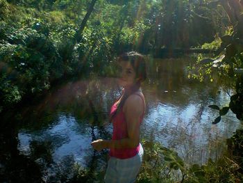 Woman standing by lake in forest