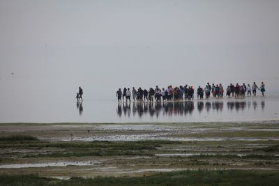 People standing in water against sky