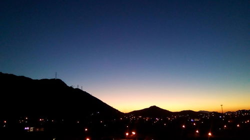 Illuminated city against clear sky at night