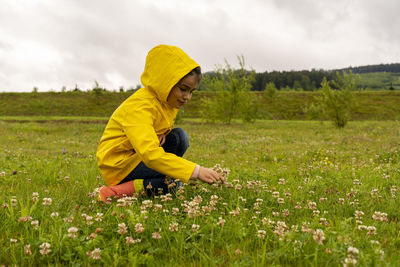 Side view of a boy with yellow flowers on field