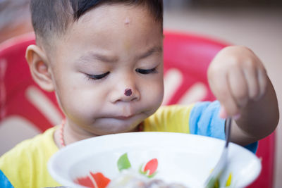 Close-up of cute boy with nose injury eating food while sitting at home