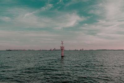 Lighthouse by sea against sky during sunset