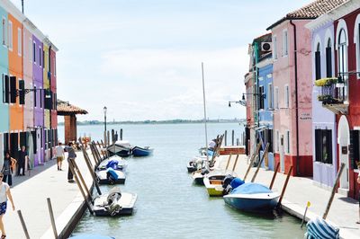 Sailboats moored on sea against buildings in city