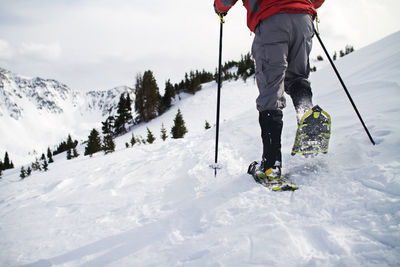 Low section of man walking on snow field