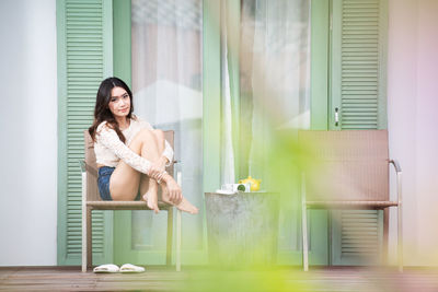 Young woman smiling while sitting on window