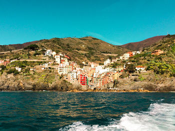 Townscape by sea against clear blue sky