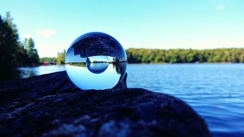 Close-up of rock by lake against sky