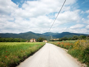 Road amidst field against sky