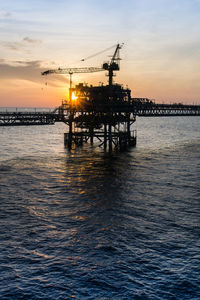 Scenic view of oil field against sky during sunset