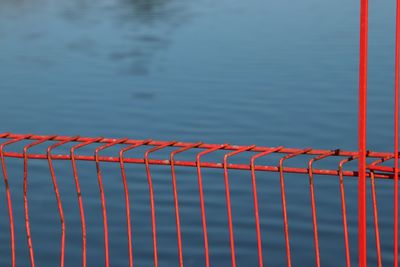 Close-up of metal fence against blue lake