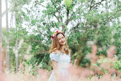 Portrait of smiling woman standing against trees