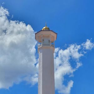 Low angle view of lighthouse by building against sky