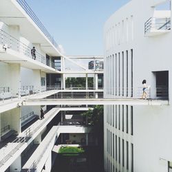 People walking on building in university against clear sky