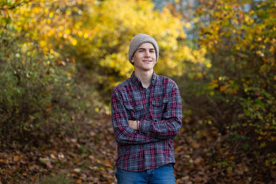 Confident teen boy in beanie stands in woods in pacific northwest.