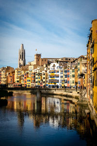 Buildings by river against sky in city