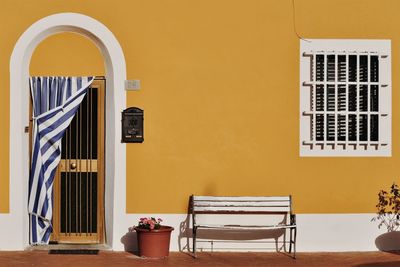 Empty chairs and table against yellow building