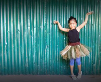 Portrait of cute girl in tutu standing against wall