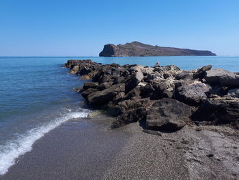 Rock formation on beach against clear sky