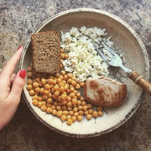 Cropped image of hand holding food in plate on table