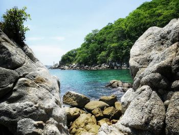 Scenic view of rocks by sea against sky