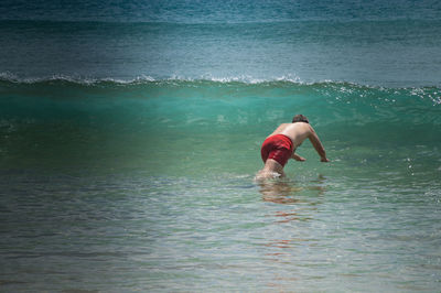 Full length of shirtless man swimming in sea