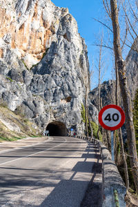 Road sign on rock against sky