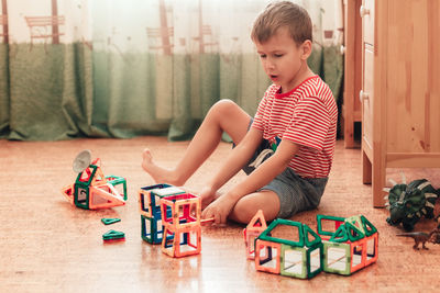 Boy playing with toy sitting on floor