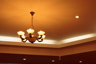 Low angle view of illuminated light bulb hanging on ceiling