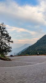Road by trees against sky during sunset