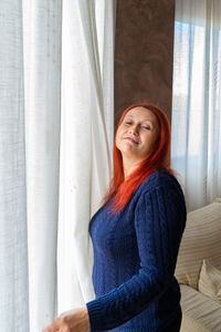 Portrait of smiling woman standing by window