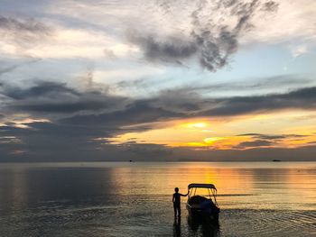 Silhouette of person with motorboat at lake during sunset