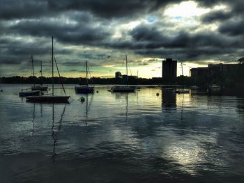 Boats in harbor against cloudy sky