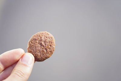 Close-up of hand holding ice cream against white background