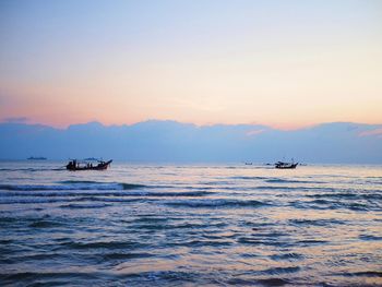 Boat sailing in sea against sky during sunset