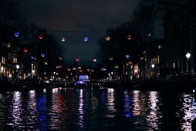 Illuminated city by river at night