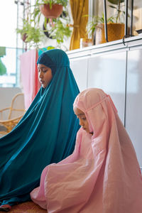 Cute girls in hijab praying at home