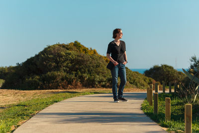 Woman standing on footpath against clear sky