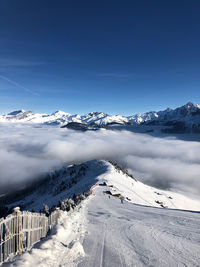 Scenic view of snow covered mountains against blue sky