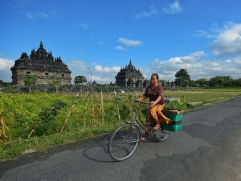 Man riding bicycle on street against sky