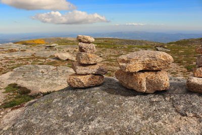 Stack of stones on rock against sky