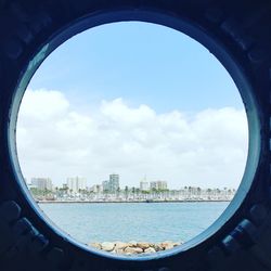 Close-up of cityscape by sea against sky